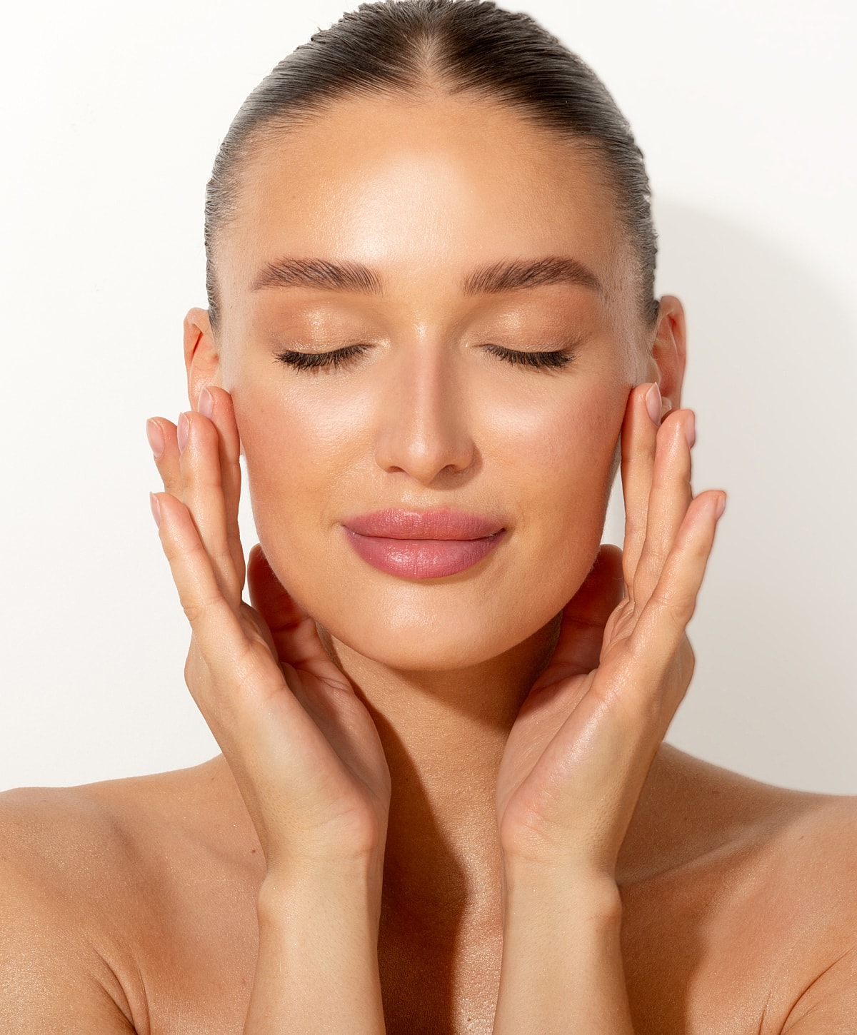 Woman with gray hair gently touching her face.
