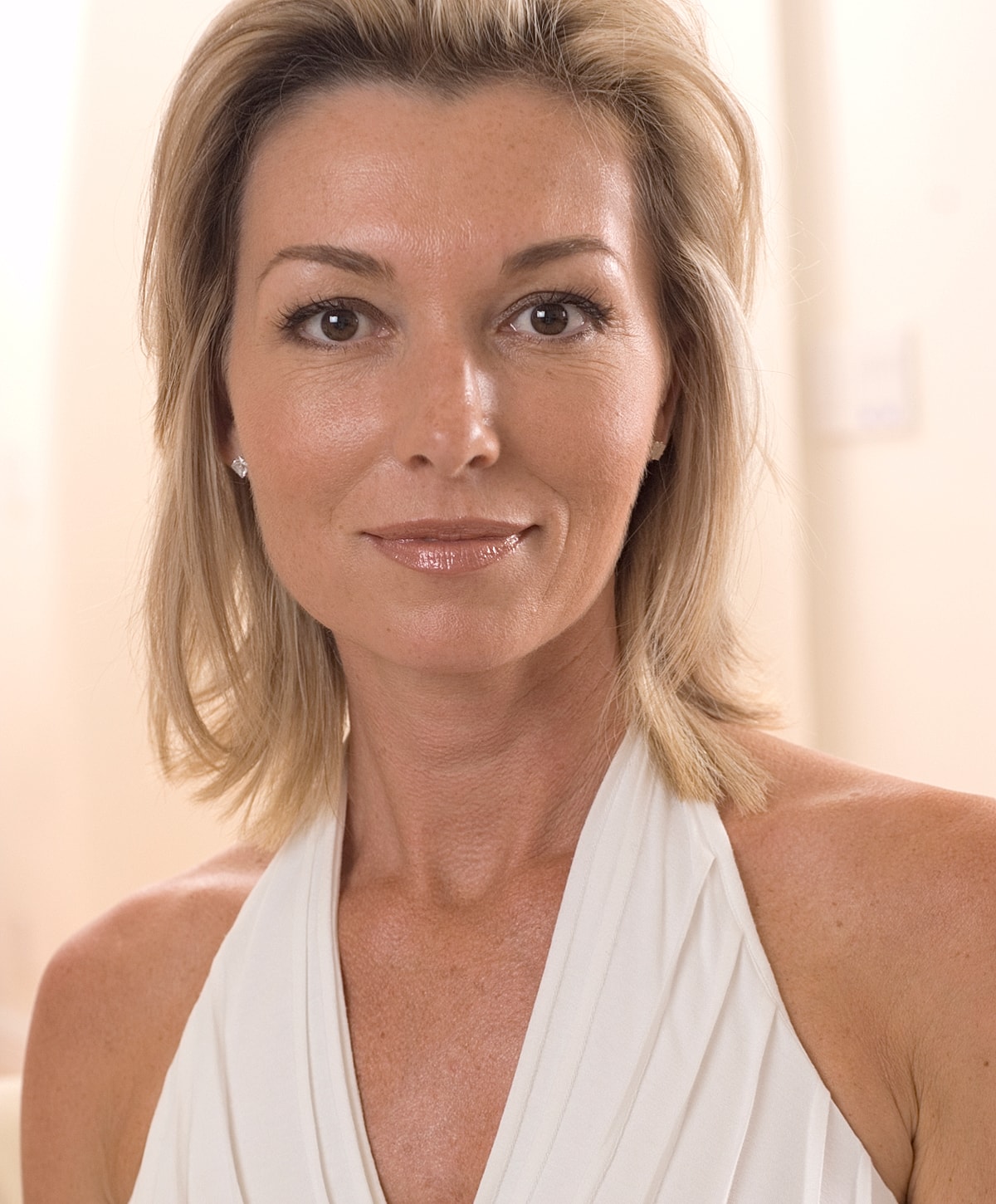 Woman with gray hair gently touching her face.