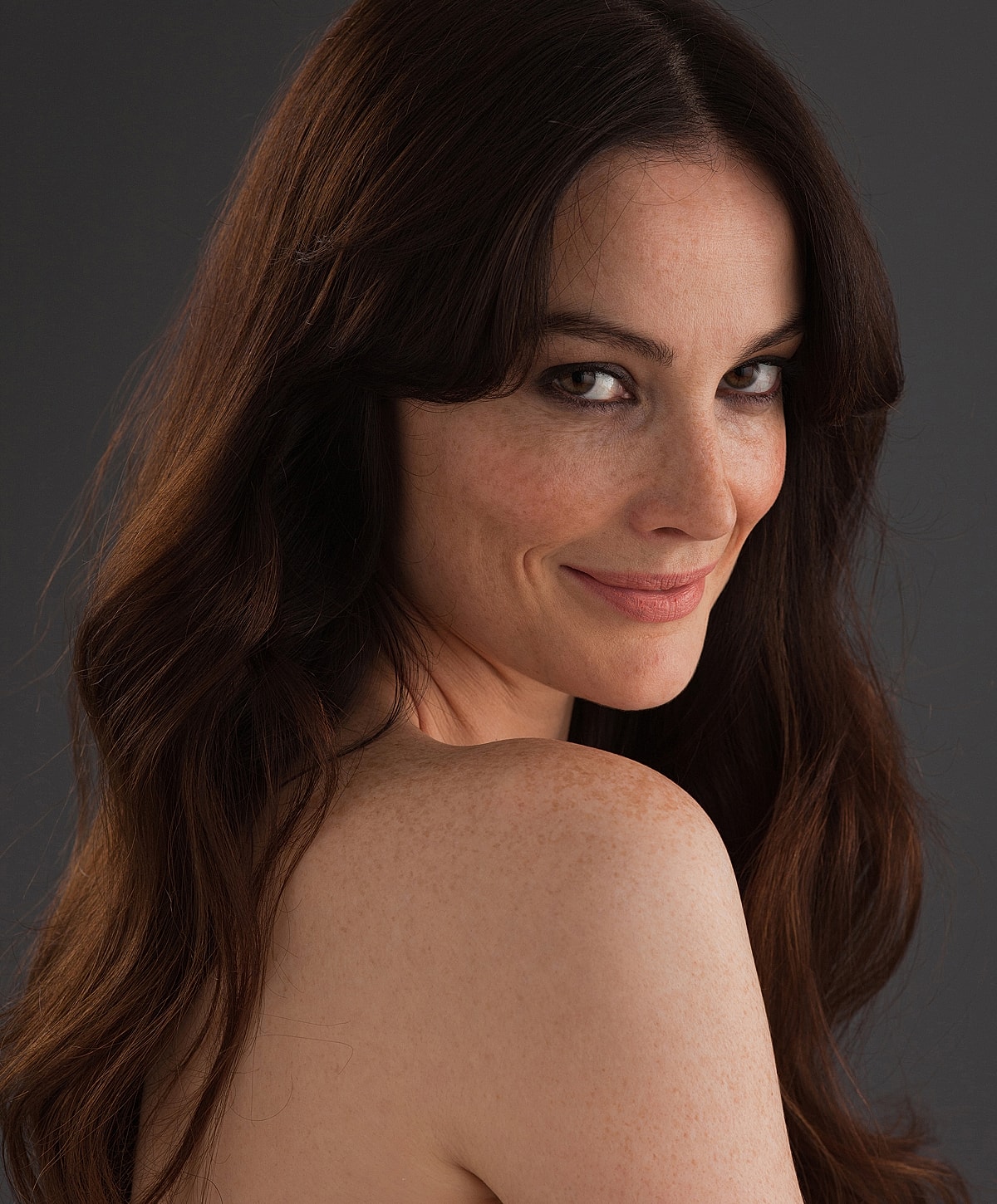Woman with long hair smiling softly at camera.