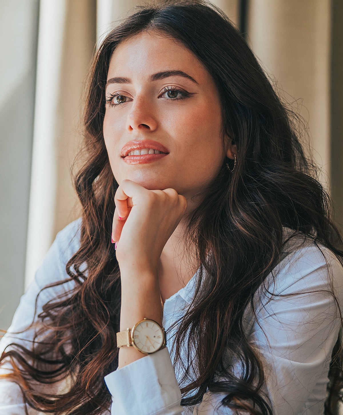 Woman resting chin on hand, thoughtful expression.