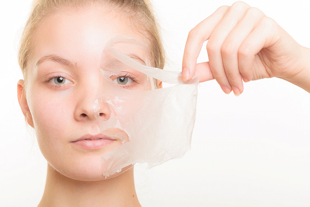 Woman removing a facial mask piece.