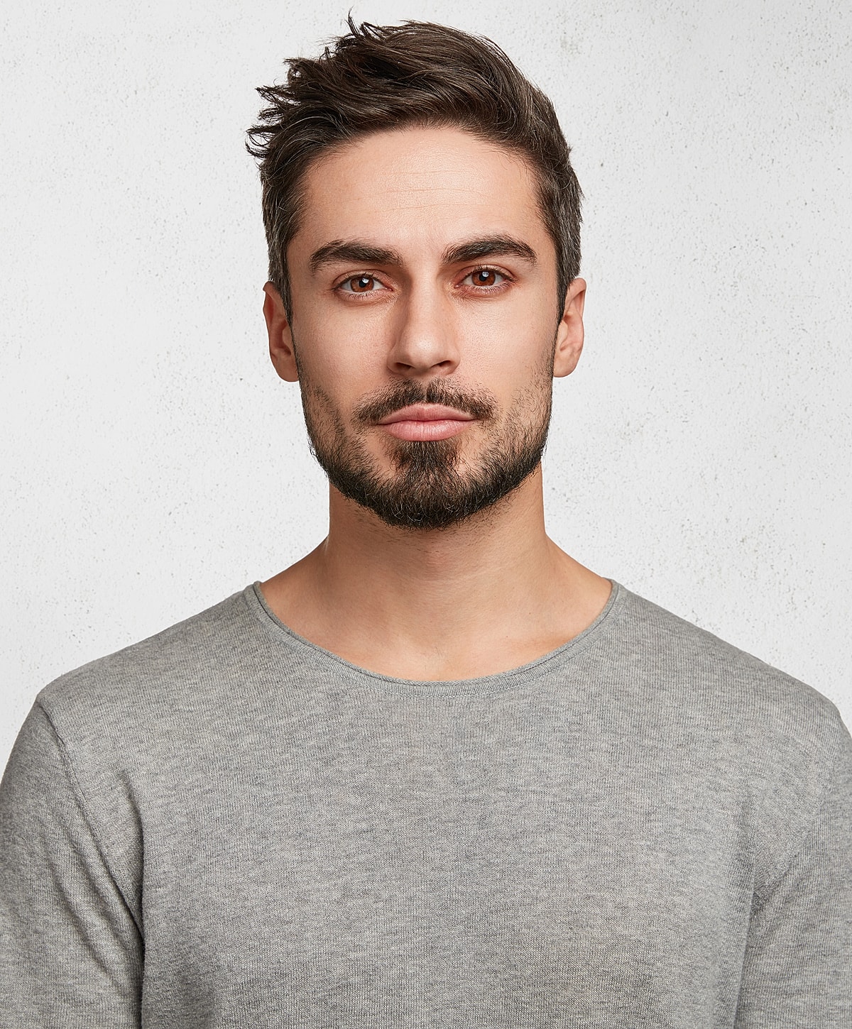 Man with beard wearing gray shirt, neutral background.