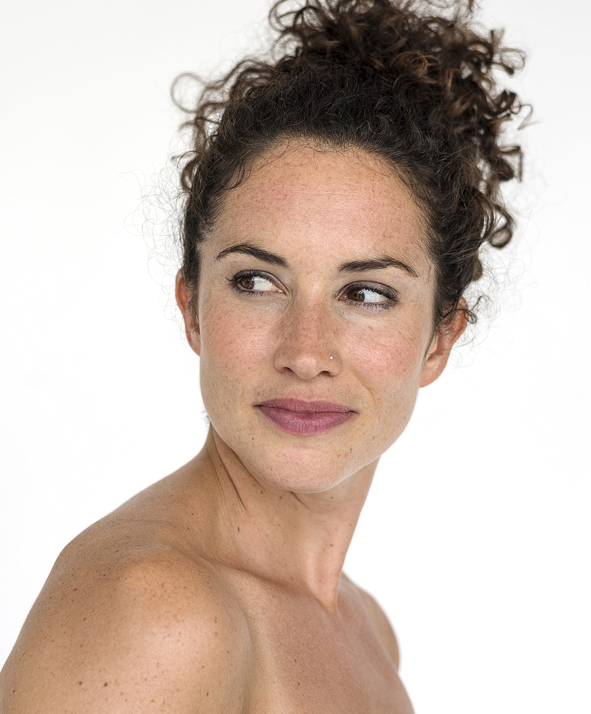 Woman with curly hair looking over her shoulder.