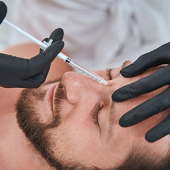 Administering cosmetic injection on patient's forehead.
