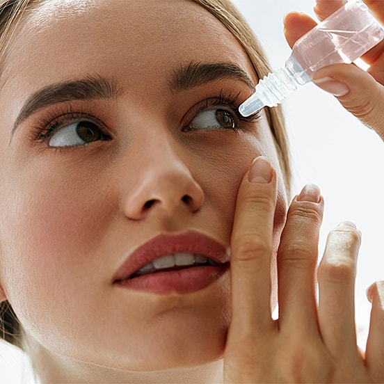 Woman applying skincare serum to her face.