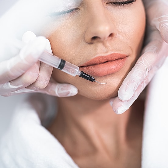 Cosmetic treatment on woman's lips with syringe.