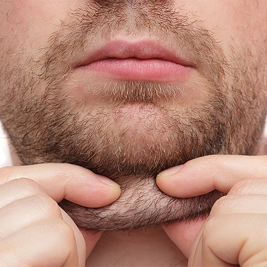 Person pulling at facial hair below chin.