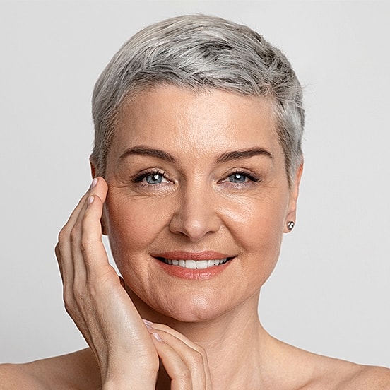 Smiling woman with short silver hair and makeup.