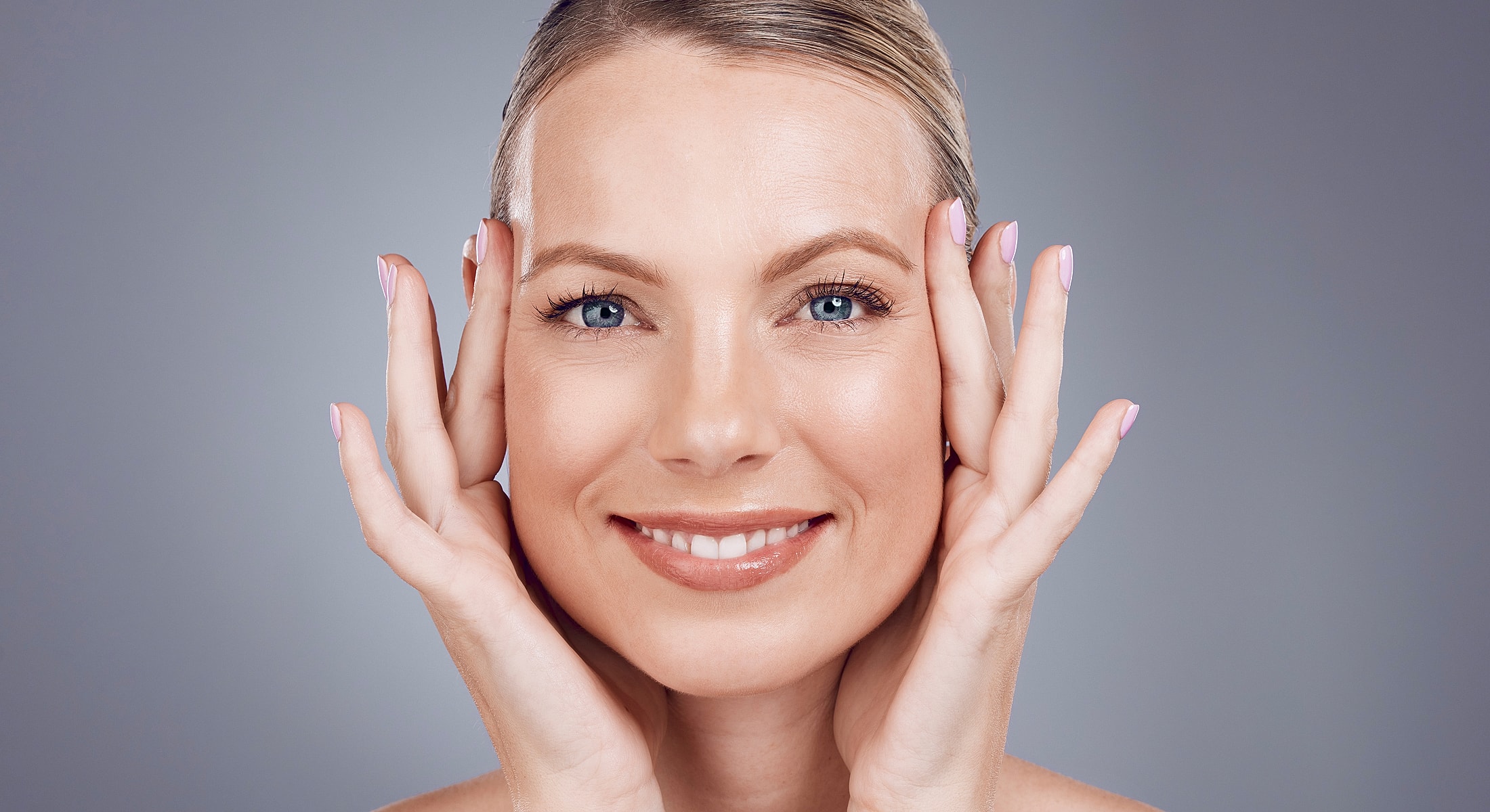 Smiling woman with hands on her face.