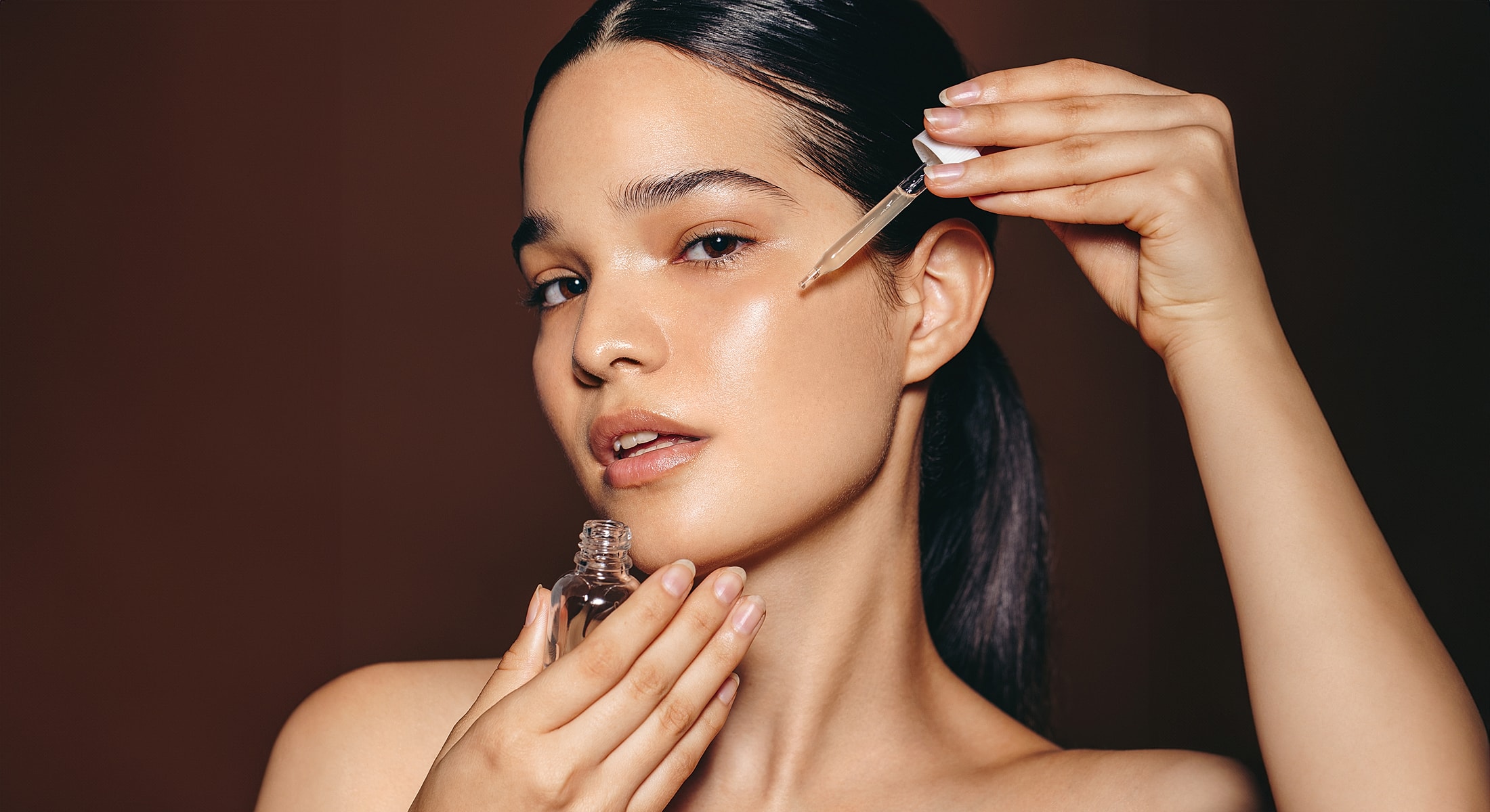 Woman applying facial oil with dropper.