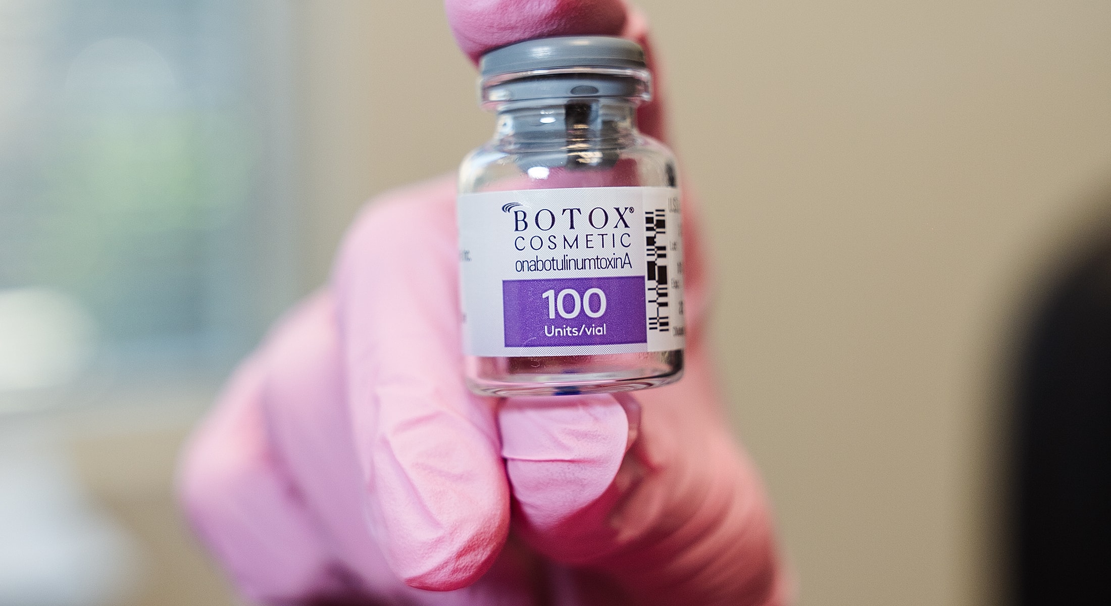 Botox cosmetic vial held by gloved hand.