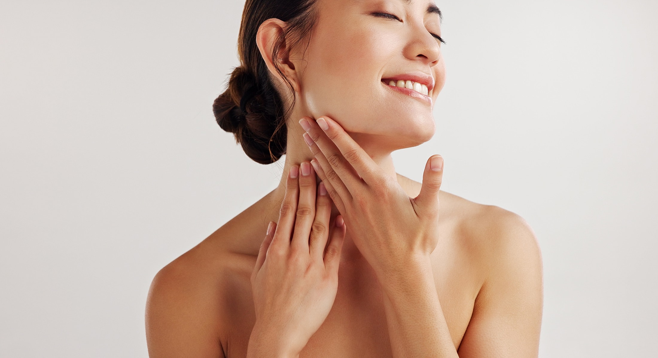 Woman gently touching her face, smiling happily.