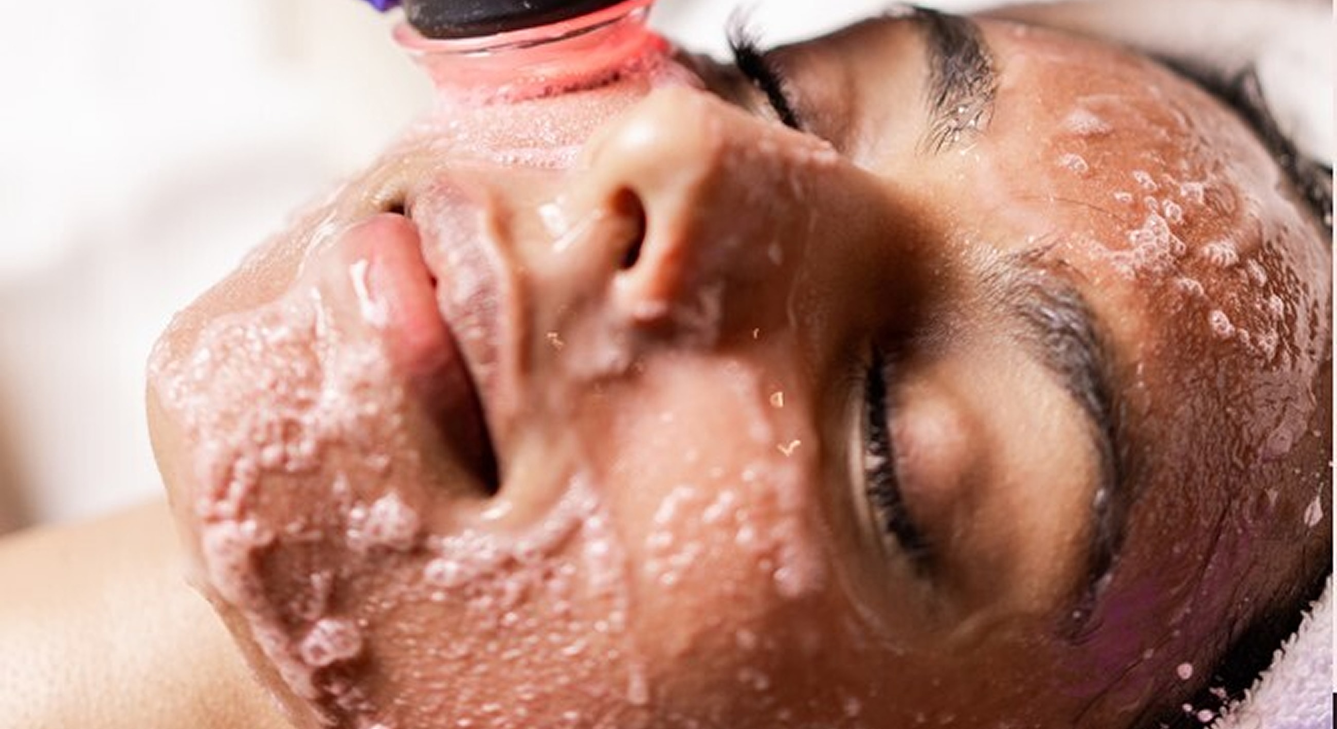 Woman receiving a facial treatment with cleansing foam.