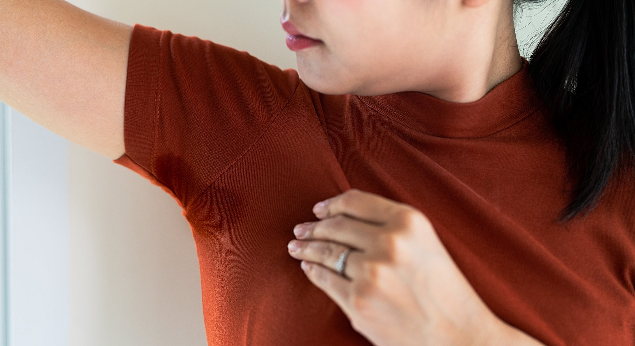 Woman checking underarm sweat stain on shirt.
